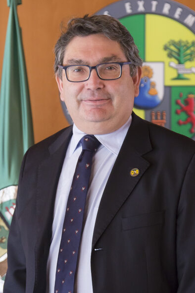 Foto oficial tipo retrato de Jacinto Martín Jiménez delante de una pared con la bandera y el logo de la universidad.
